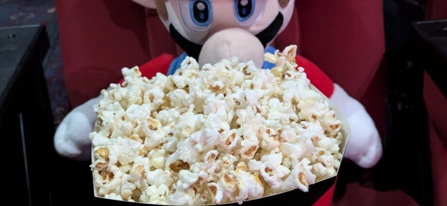 A photo of mario (plush) enjoying a big bag of popcorn!